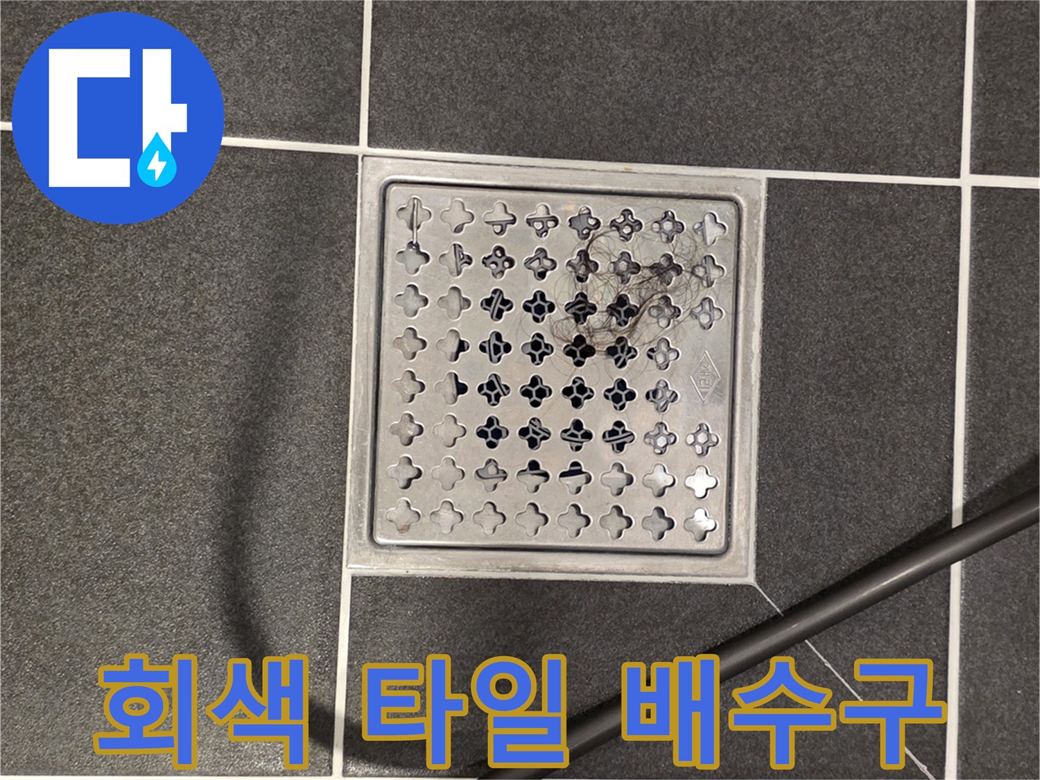어두운 색상의 타일 바닥과 금속제 배수구 덮개 모습