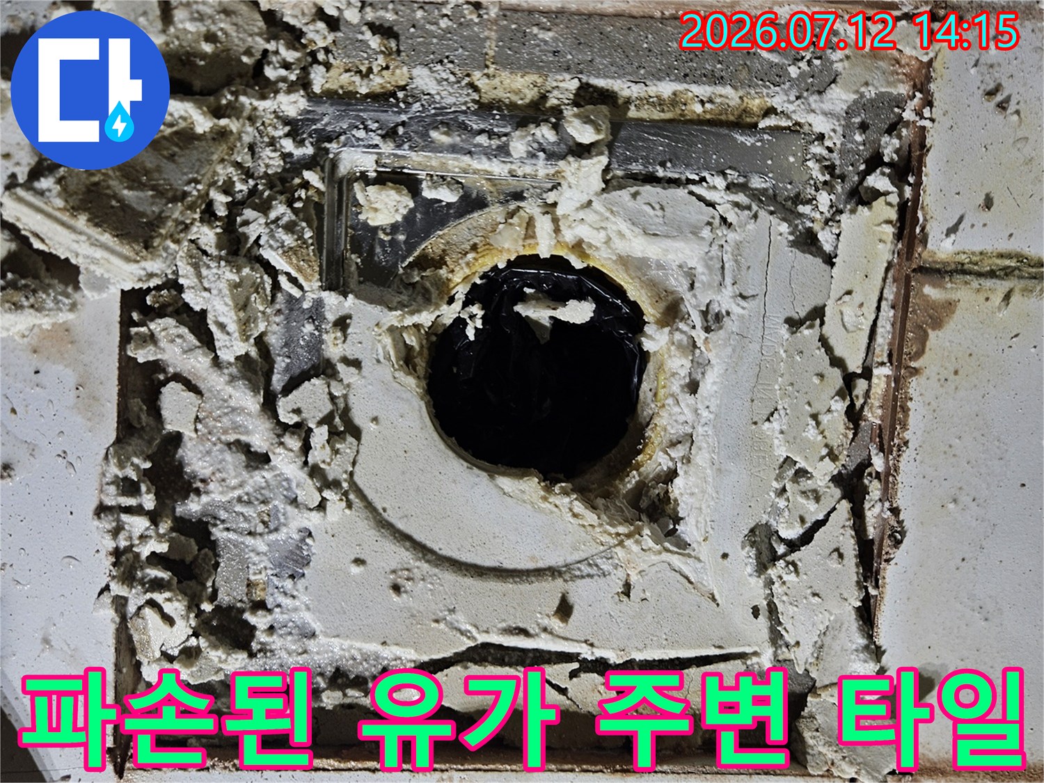 부서진 타일 조각과 노출된 배수구 내부