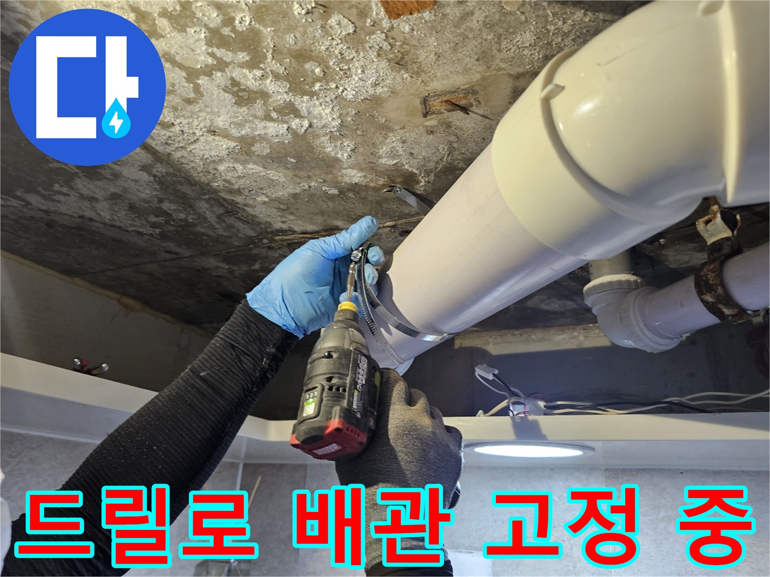 천장 내부 하수관 연결 부위를 전동 드릴로 조이는 모습