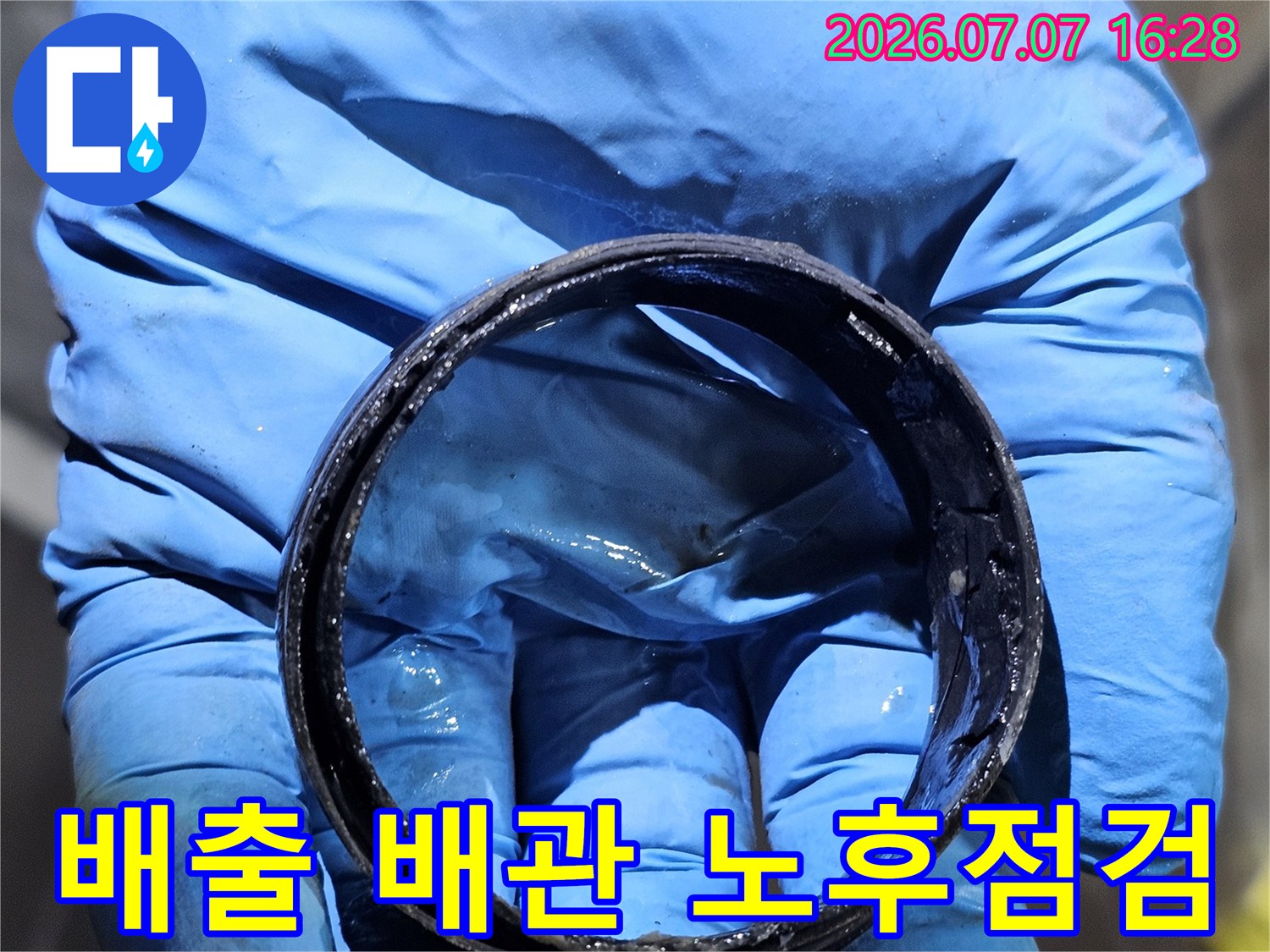 파란색 장갑을 끼고 화장실 천장 안의 낡은 배송용 배수 배관 부품들을 점검하는 모습
