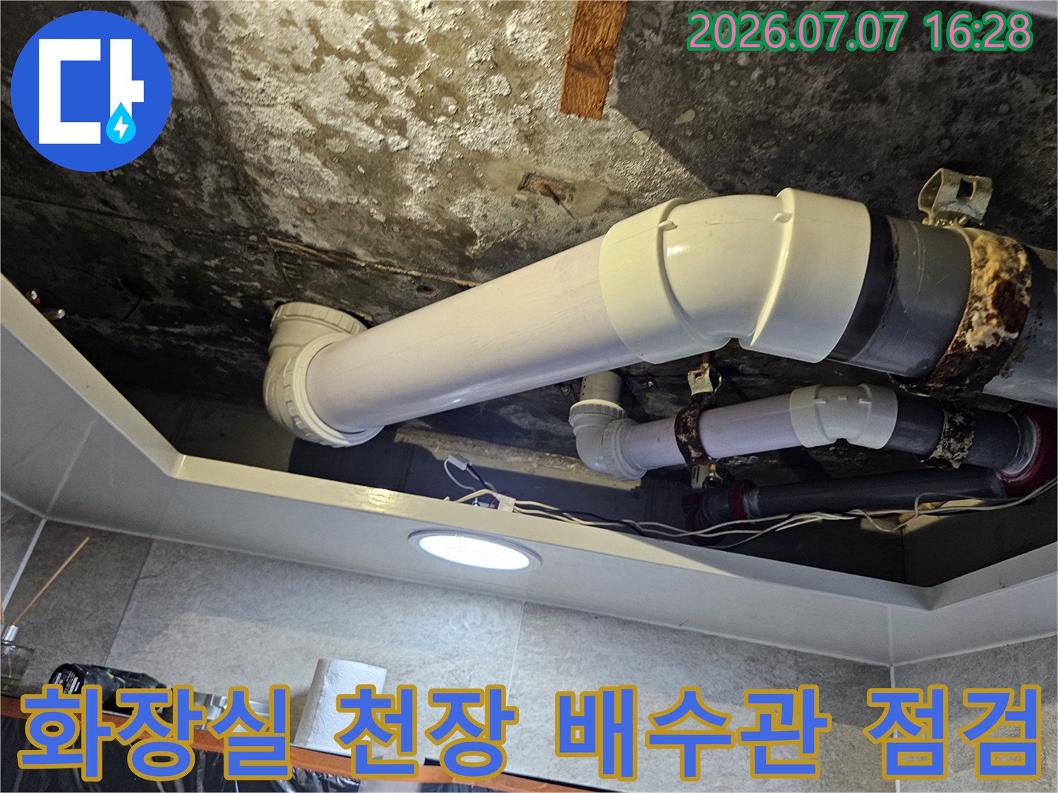 화장실 천장 내부에 노출된 흰색 배수 배관과 연결 부위 점검 모습