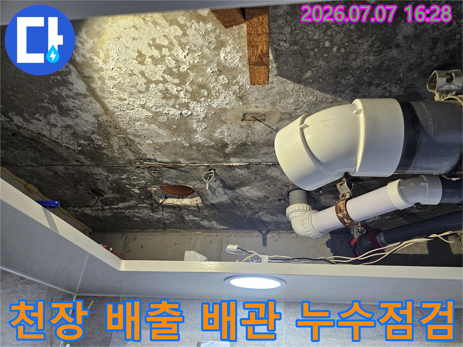 화장실 천장 내의 노후된 하수 배관과 연결 부위의 손상 상태를 촬영한 이미지