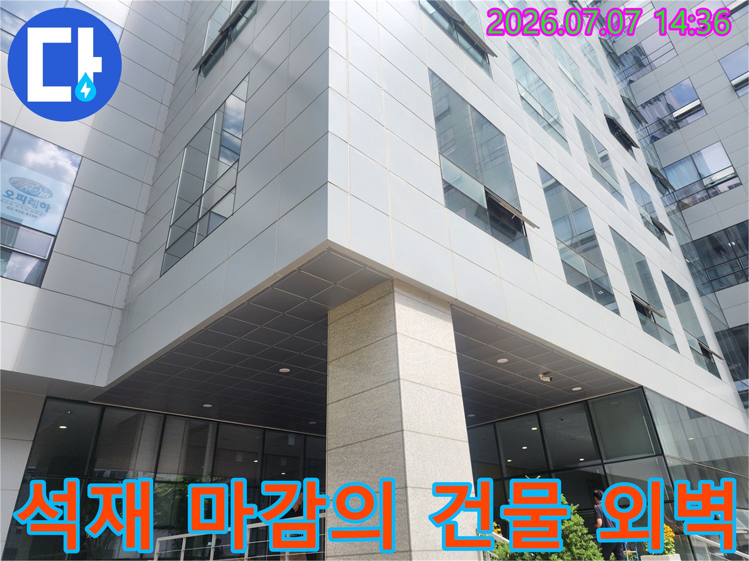 세련된 석재 패널과 통유리로 구성된 상업용 빌딩 입구 전경