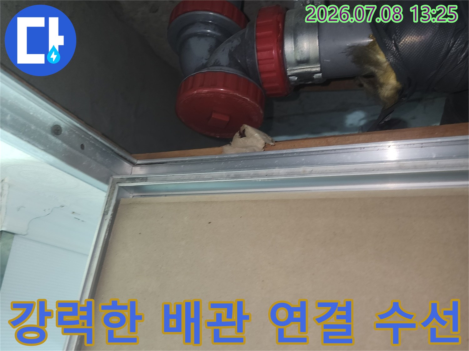 붉은색 커버가 씌워진 하수구 배관 부품의 교체 완료 모습