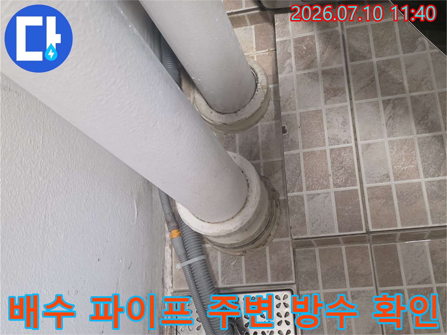 흰색 배수관과 트랩 부근의 균열 및 마감 불량 상태를 촬영한 모습