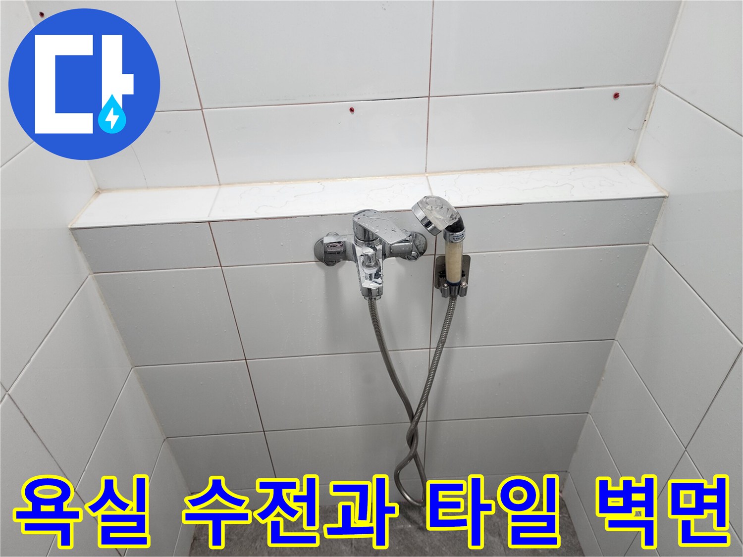 벽면에 설치된 샤워 수전과 하얀색 타일의 마감 상태를 나타냅니다.