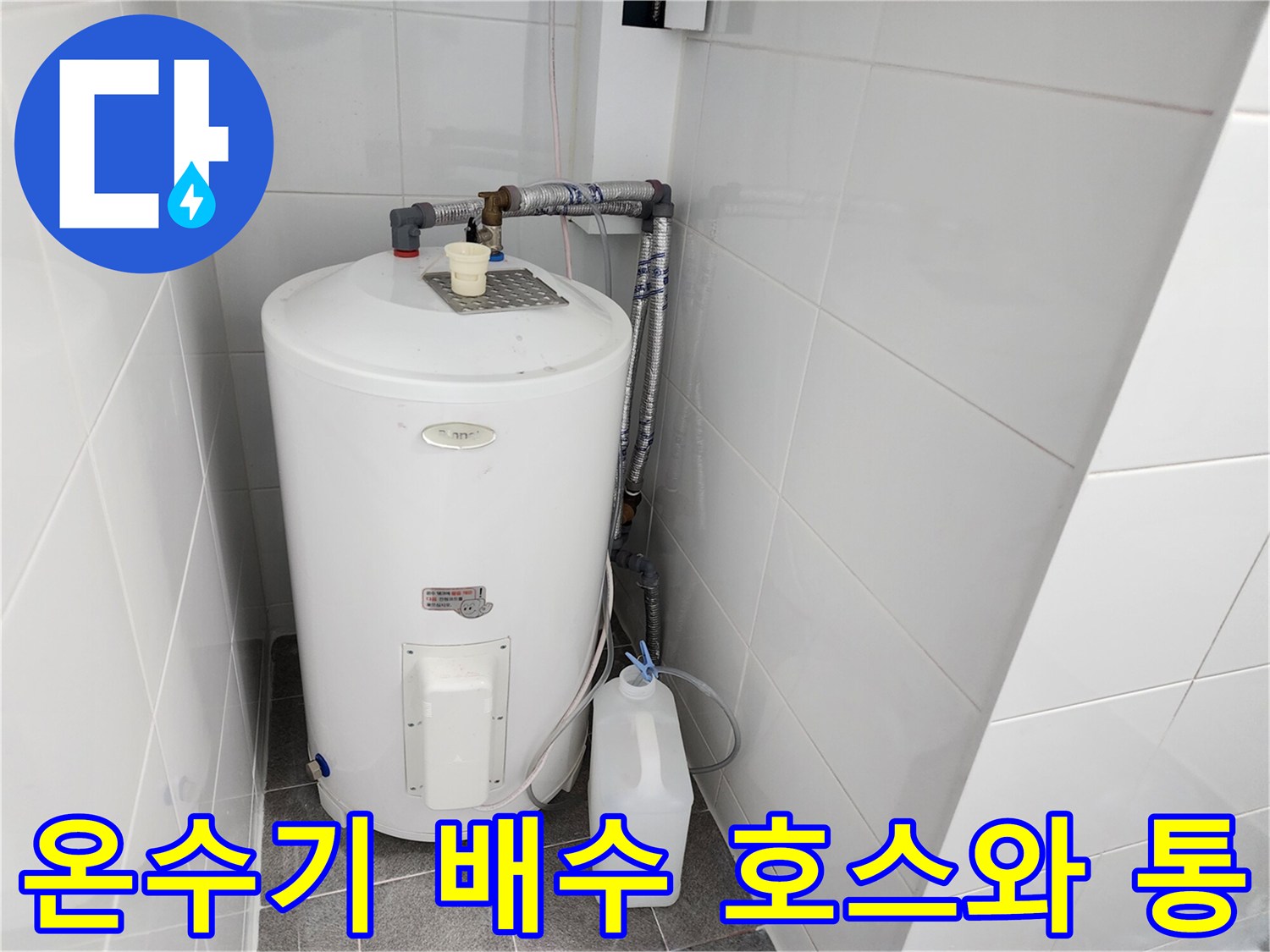 온수기 아래 흰색 통과 연결된 배수 라인의 모습입니다.