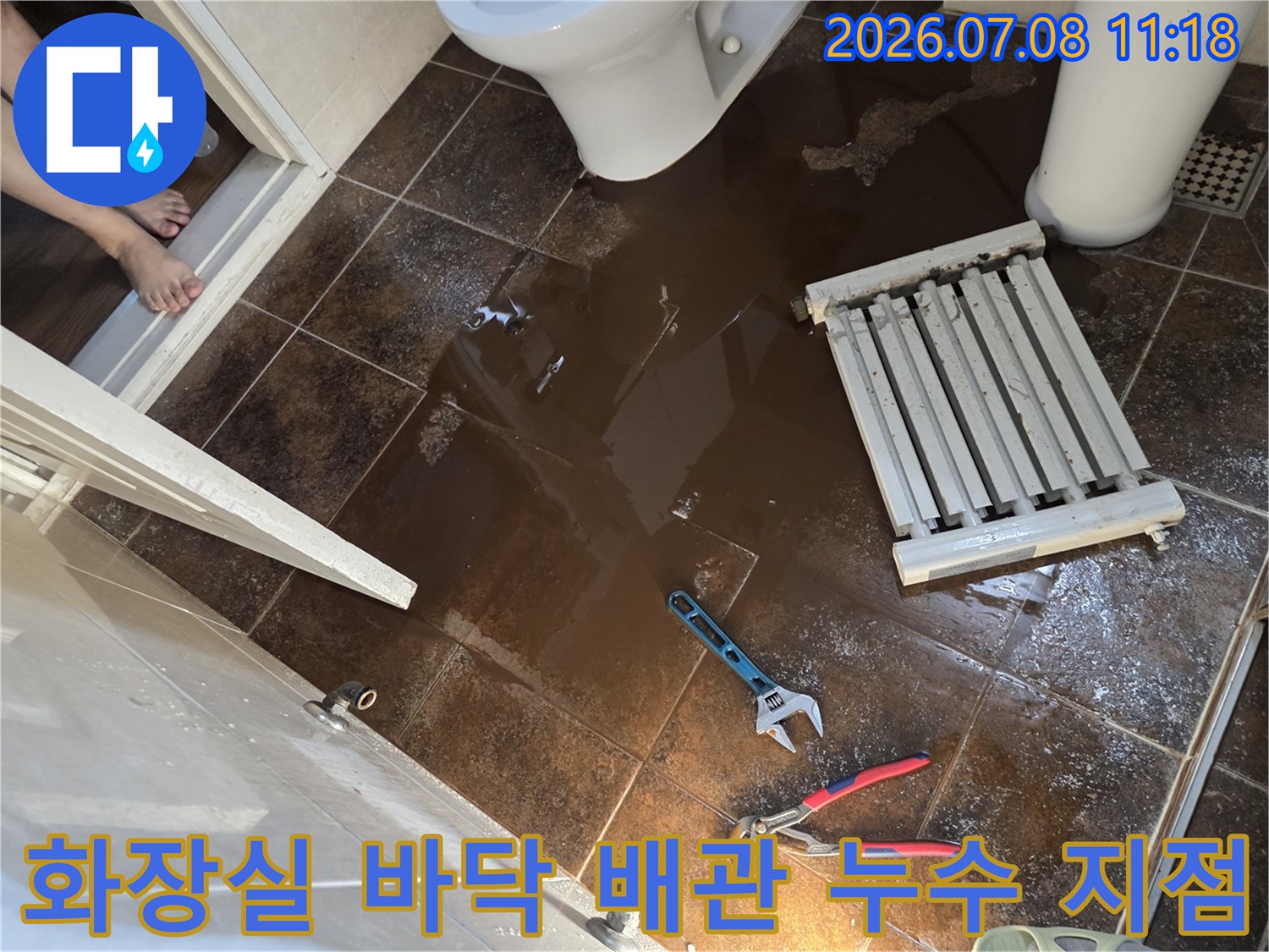 바닥에 물이 고인 화장실에서 렌치와 라지에터가 놓여 있는 누수 공사 현장