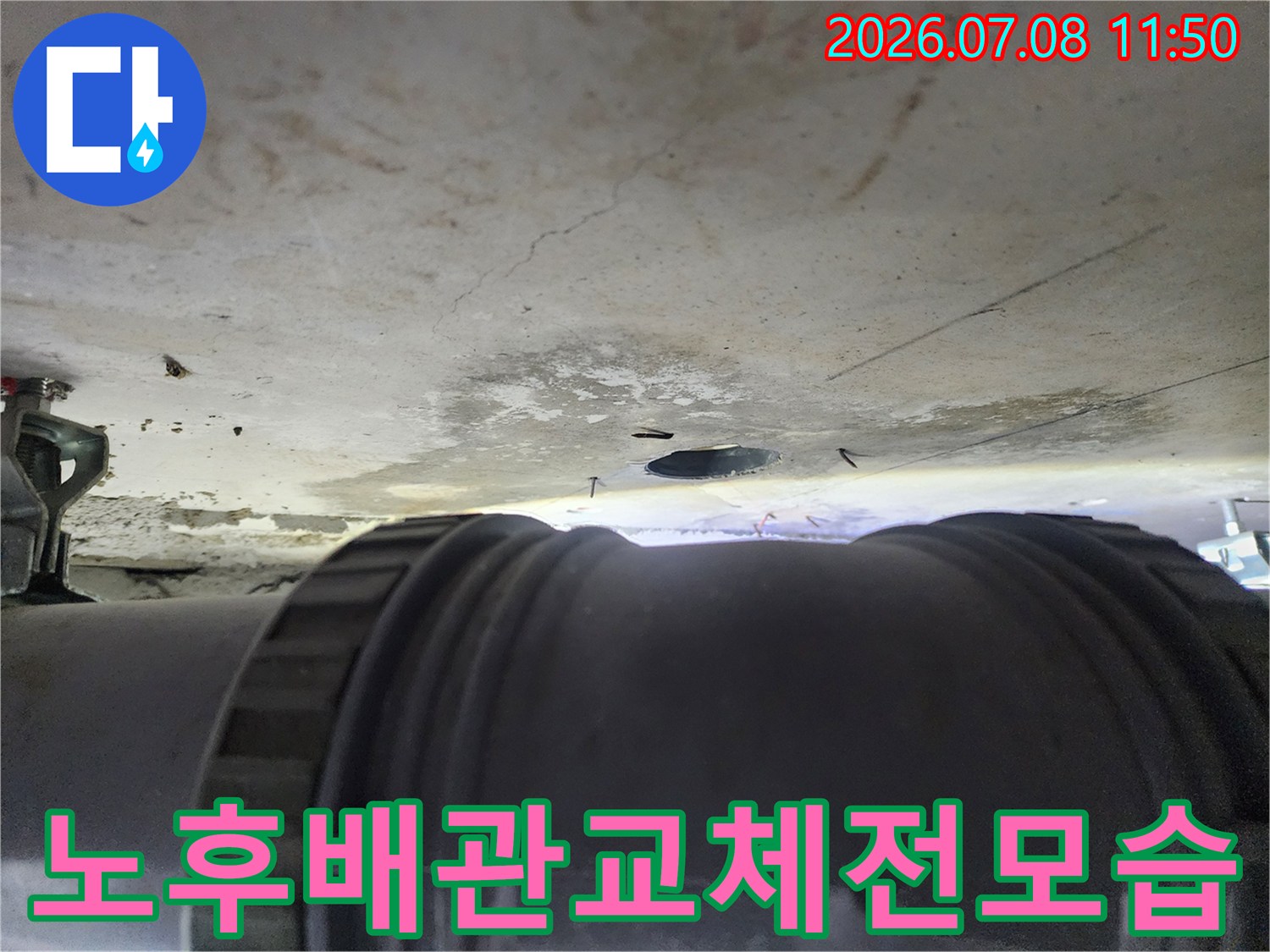 화장실 천장의 배관 연결 부위가 손상되어 물이 새는 현장을 찍은 사진