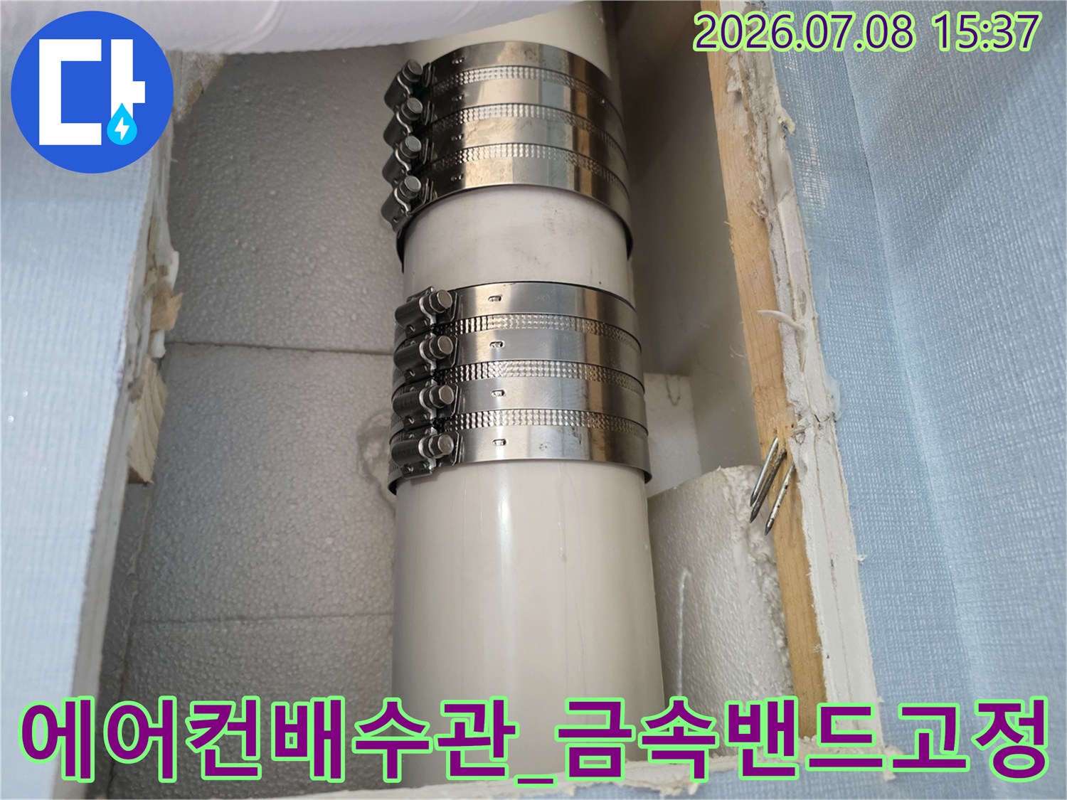 금속 밴드로 단단하게 고정된 하얀색 에어컨 배수관의 모습