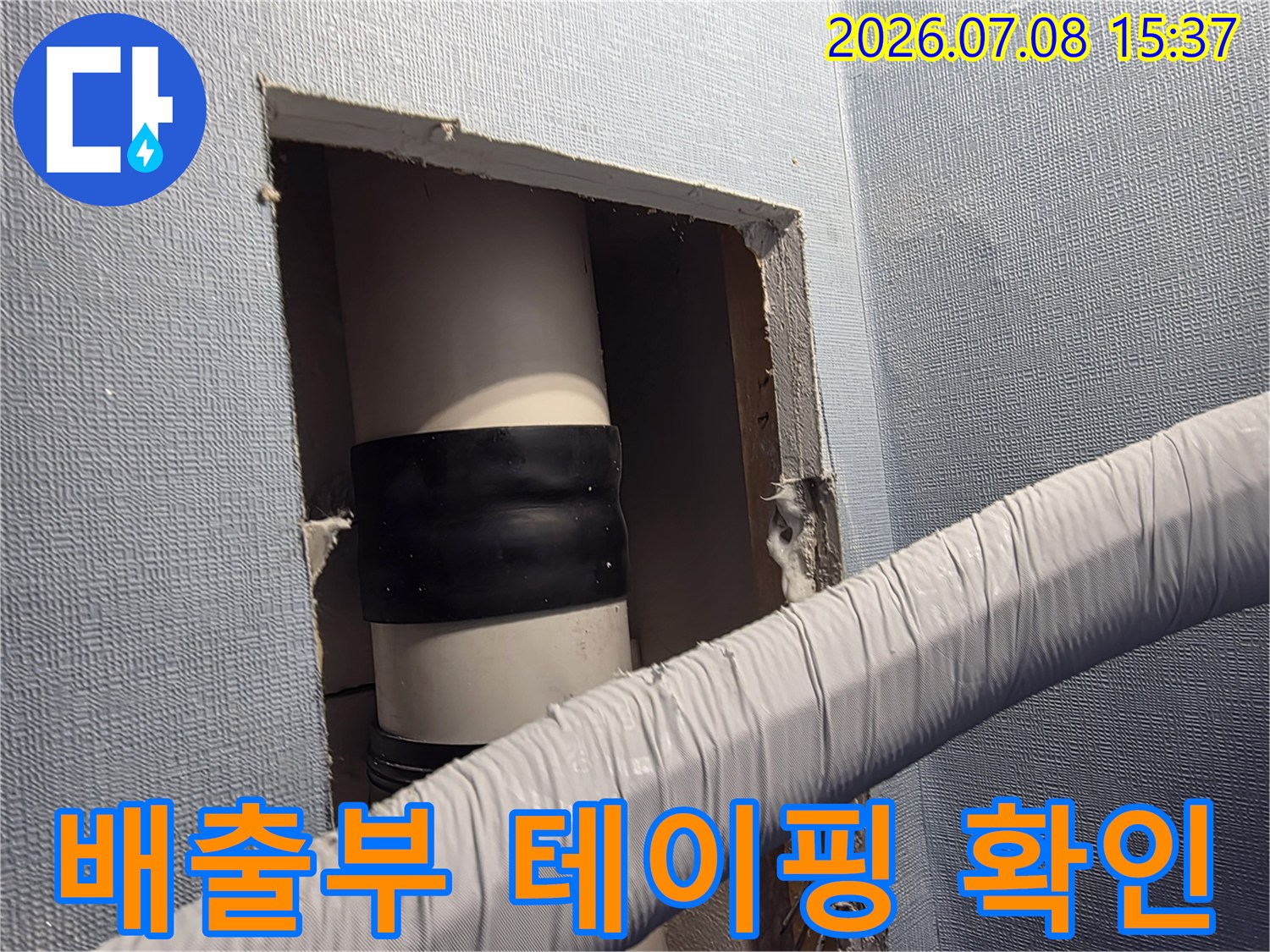 벽면을 개방하여 드러난 배송용 호스의 연결 부위에 씌워진 검은색 보호 밴드와 배관 구조
