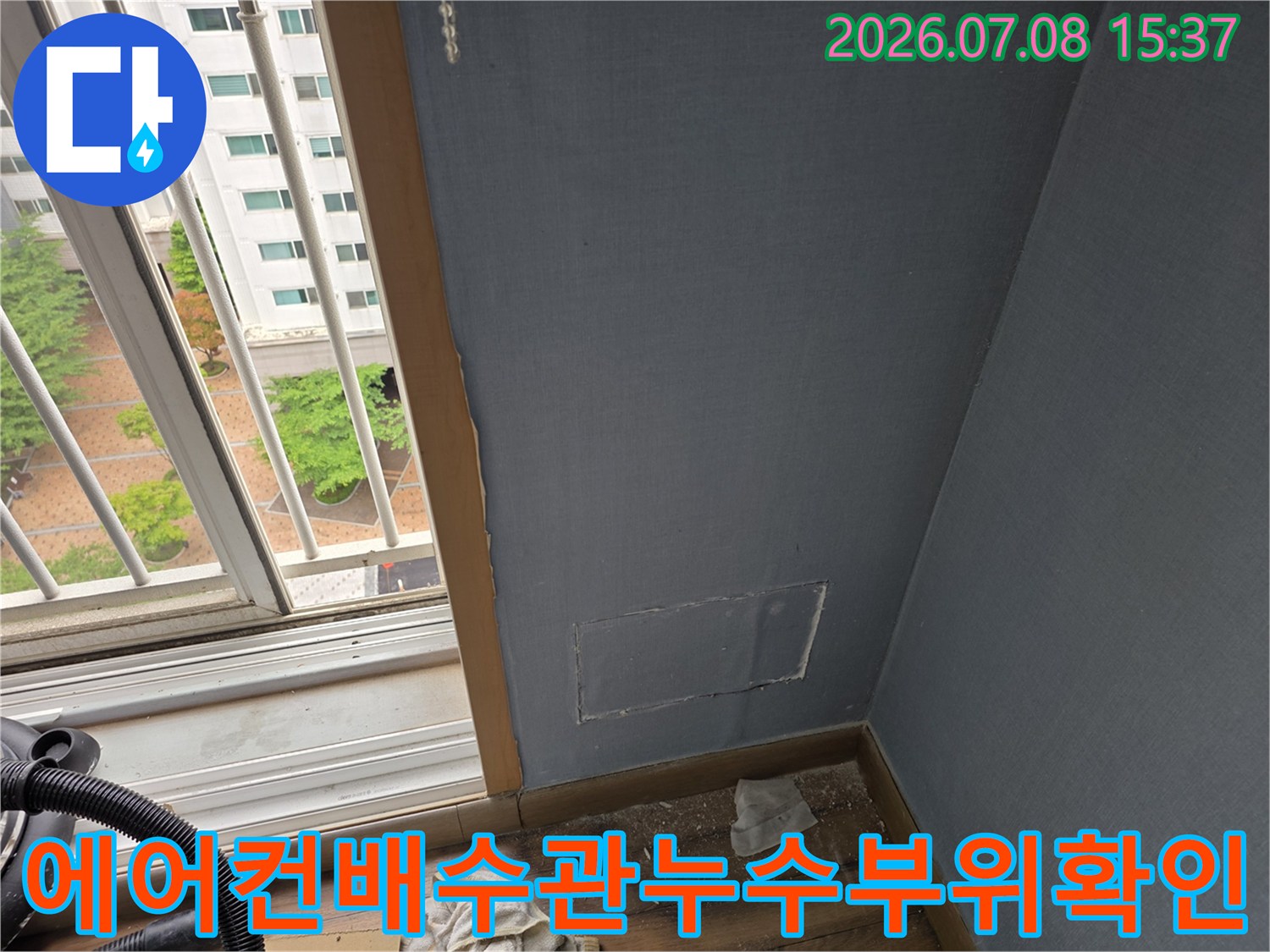 벽면을 절개하여 노출된 에어컨 배수관과 주변 바닥 상태를 점검하는 모습