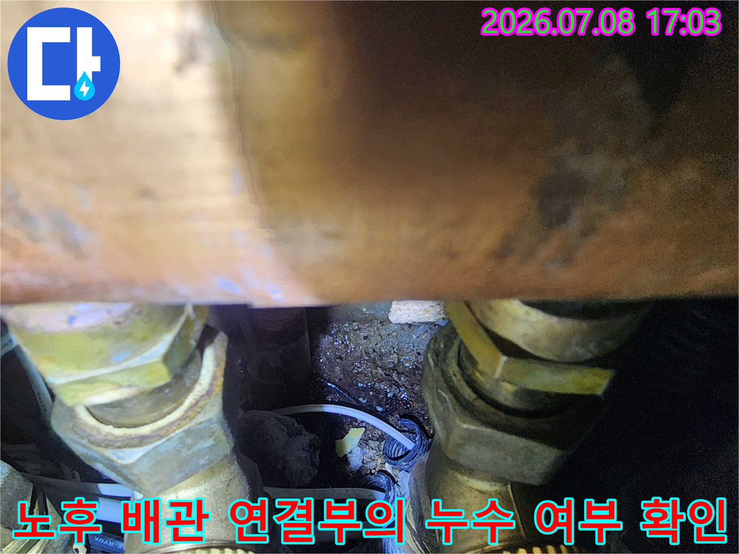 싱크대 하부 공간에 위치한 금속 소재 배관과 주변 습기 상태를 점검하는 장면