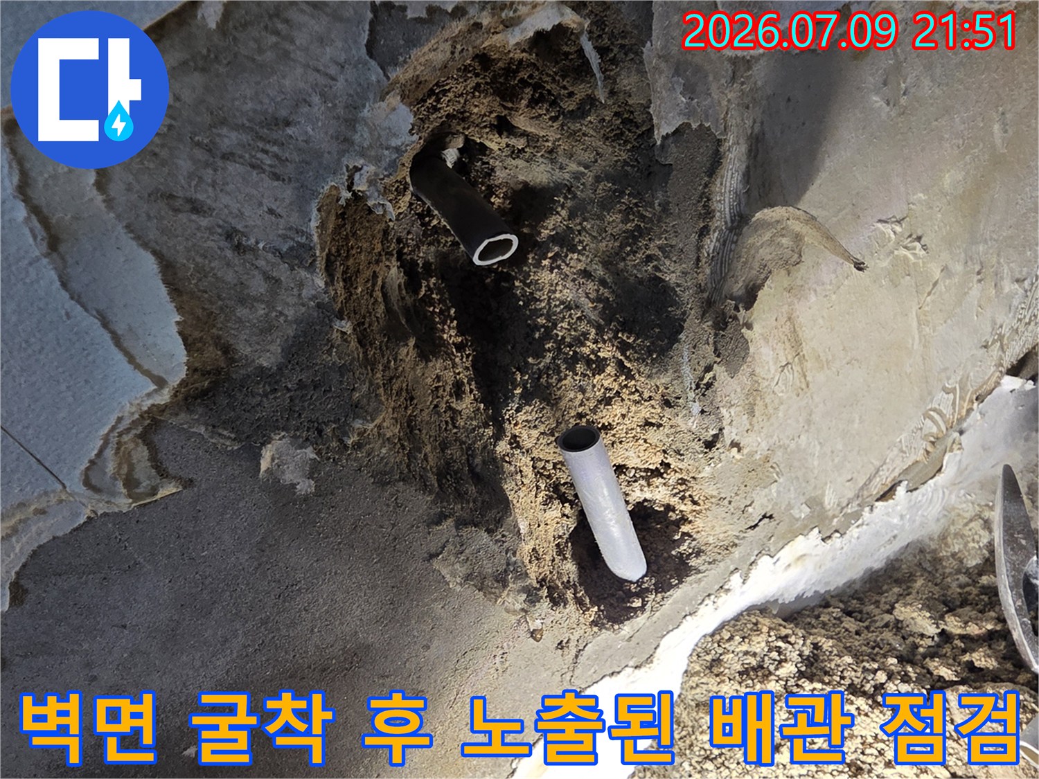 벽면을 굴착하여 발견한 누수 지점의 노출된 하얀색 배관과 주변 오염 부위