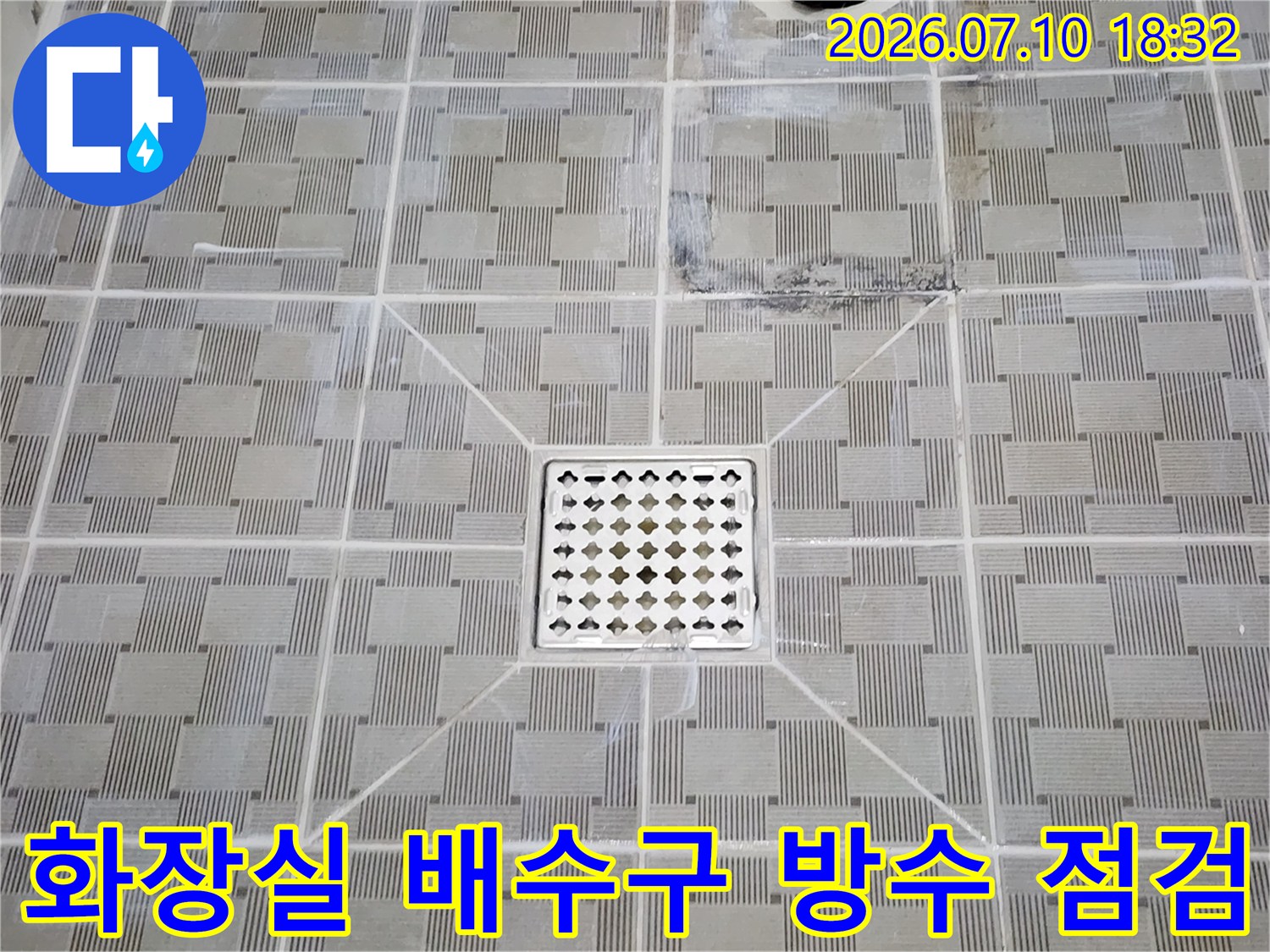 타일 바닥에 설치된 금속 소재의 화장실 배수구와 주변부 상세 모습