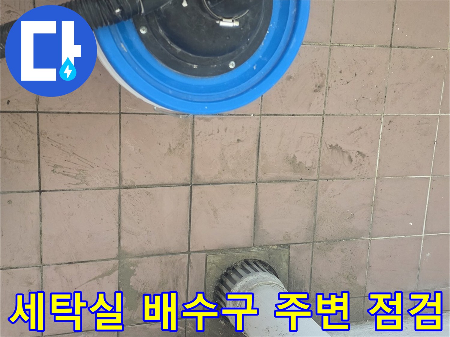 세탁실 바닥 배수구 주변의 물기 흔적과 청소용 진공 흡입 장비 모습