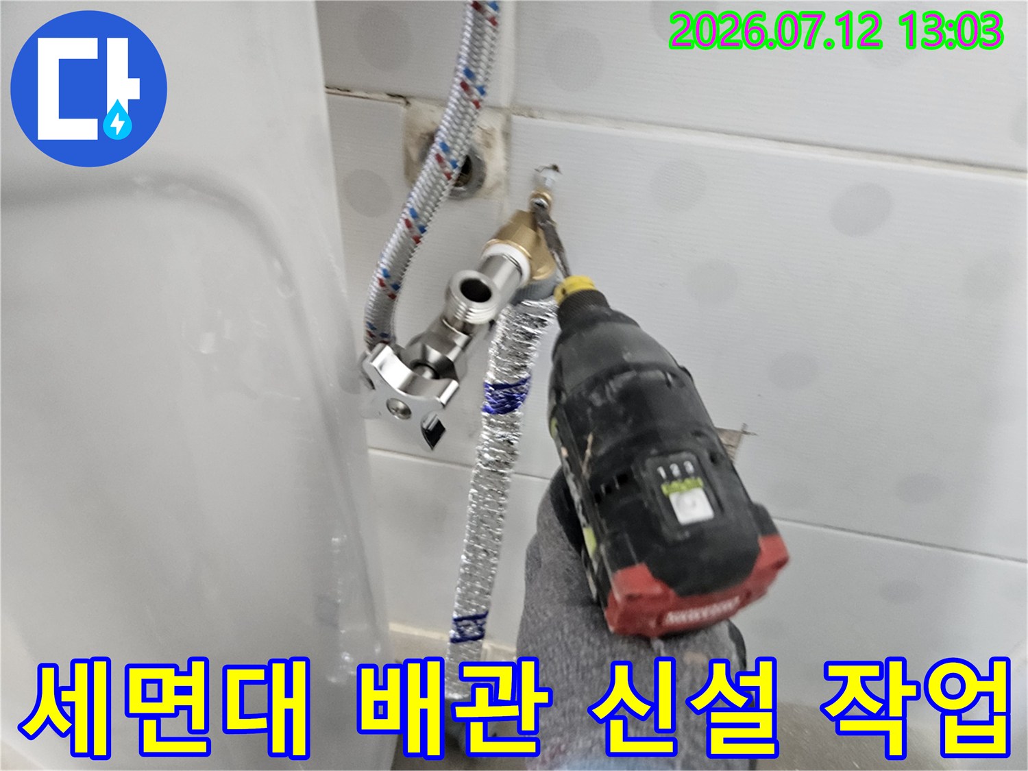 세면대 아래쪽으로 노출된 직수 배관에 보온재를 감싸고 전동 드릴로 연결 작업을 진행하는 모습
