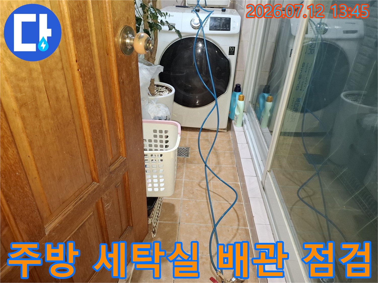 세탁기 옆을 따라 배치된 파란색 호스와 주방 공간의 누수 점검 장면