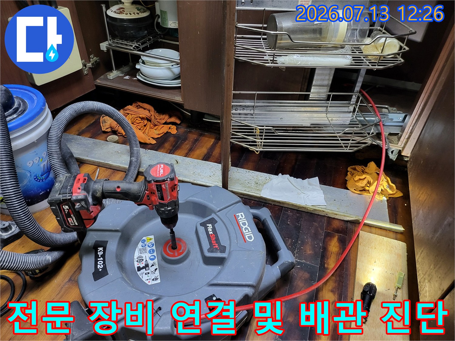 노란색과 검은색이 섞인 전문 청소 기계가 싱크대 하부 배관에 연결된 모습