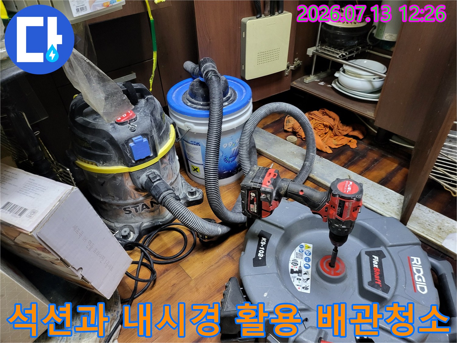 전문 장비인 석션기와 내시경 카메라를 동시에 동원하여 싱크대 아래쪽 배수관을 세척하는 모습