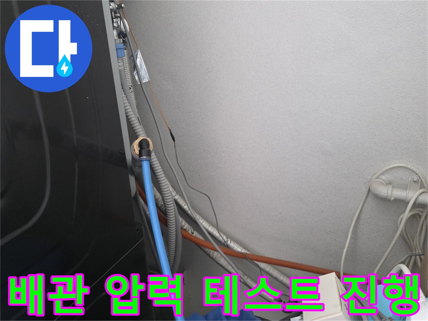 벽면 하단 배관에 연결된 파란색 공압 호스 모습