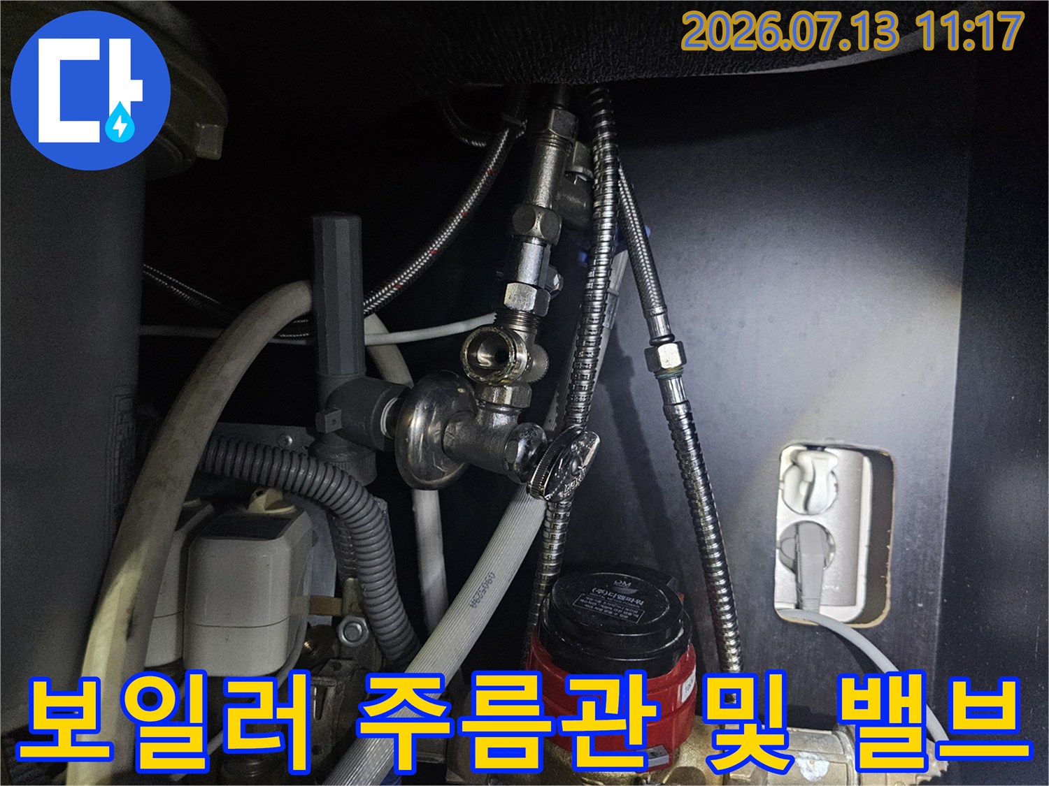 빨간색 조절 밸브와 은색 금속제 배관들이 연결된 보일러 하단부-사진