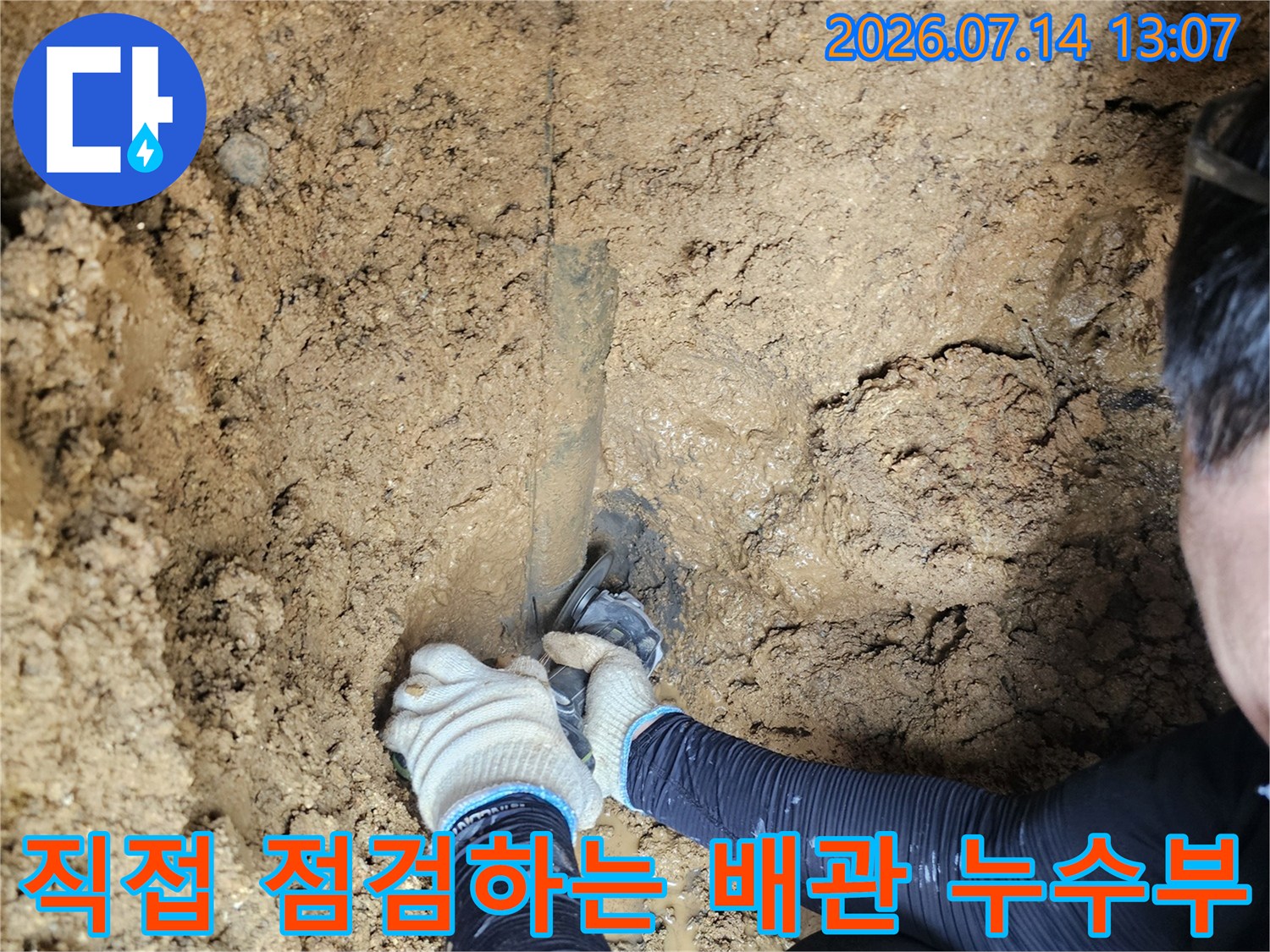 흙 속에서 발견된 노출 배관의 손상 부위를 숙련공이 파악 중인 모습