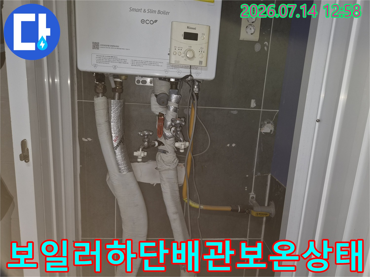 은색과 흰색 보온재로 감싸진 보일러 하부 배관들의 정면 사진