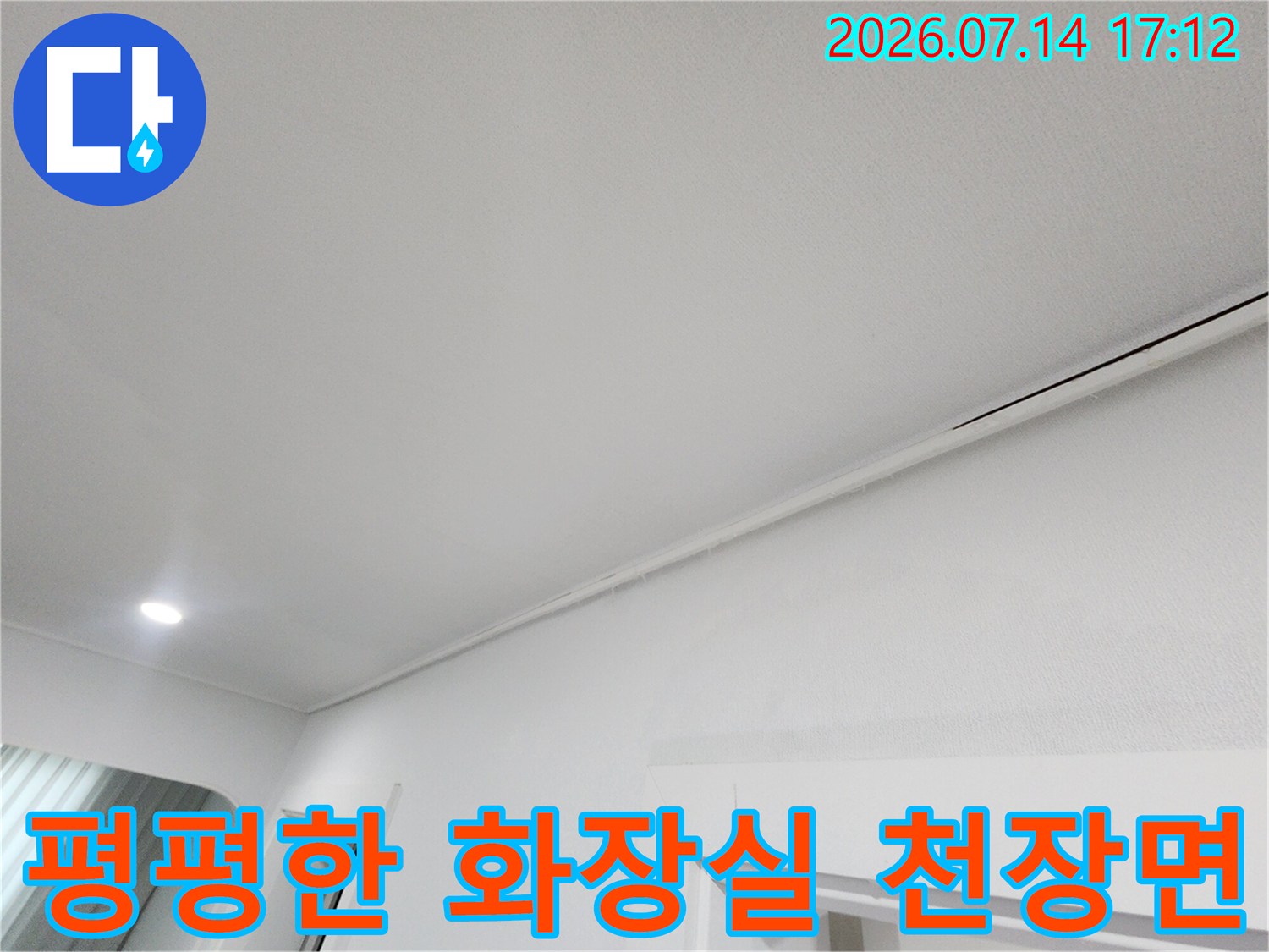화장실 입구 상부의 깨끗한 천장 마감재와 조명 시설