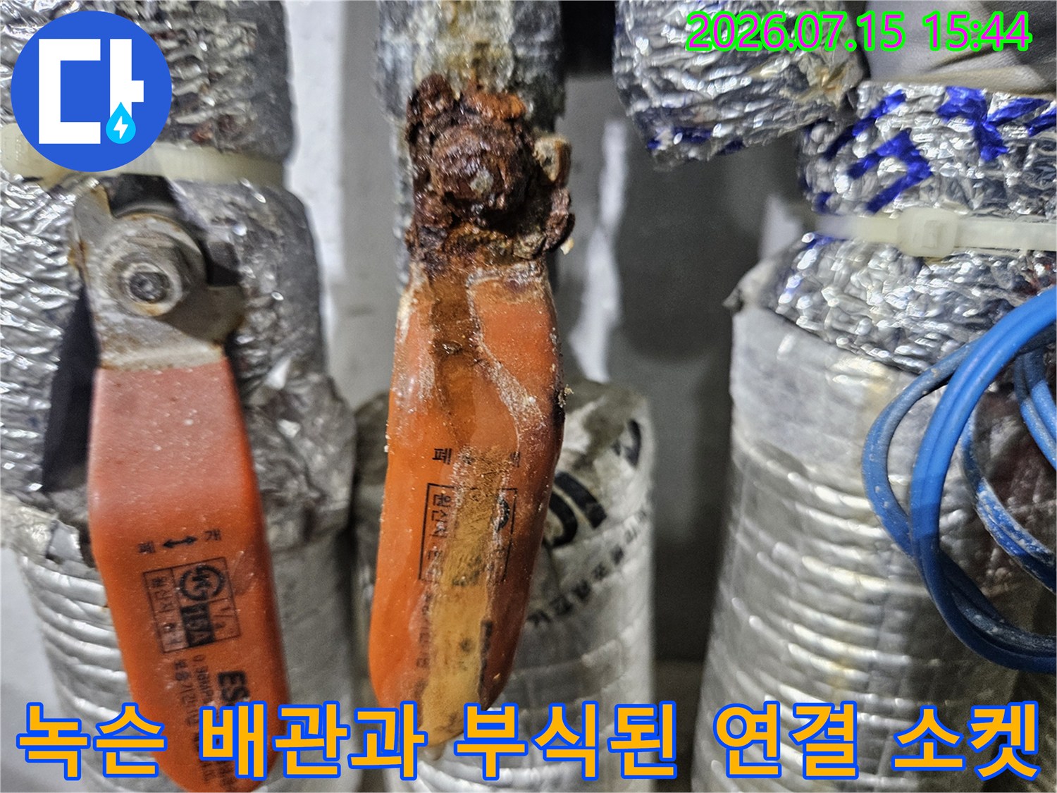 거칠고 변색된 노란색 온수 관과 녹이 슨 은색 커넥터 상세 모습