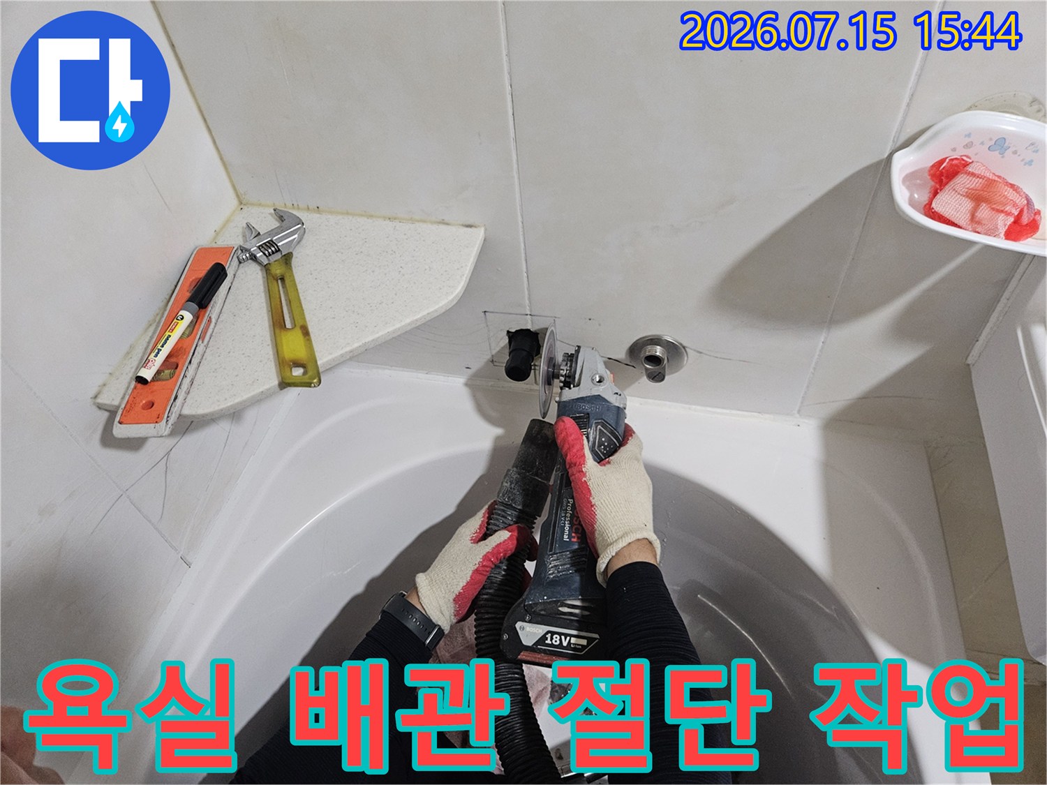 공구와 전동드릴을 사용하여 욕실 세면대 하부의 노후된 배관을 절단하는 장면