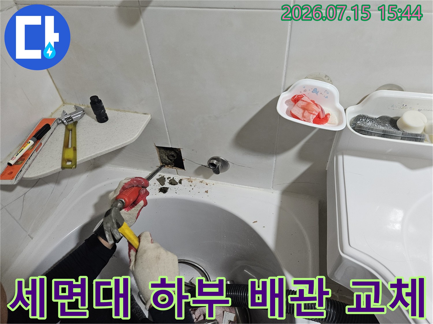 기술자가 세면대 아래에서 공구로 노후된 배관을 보수하는 장면