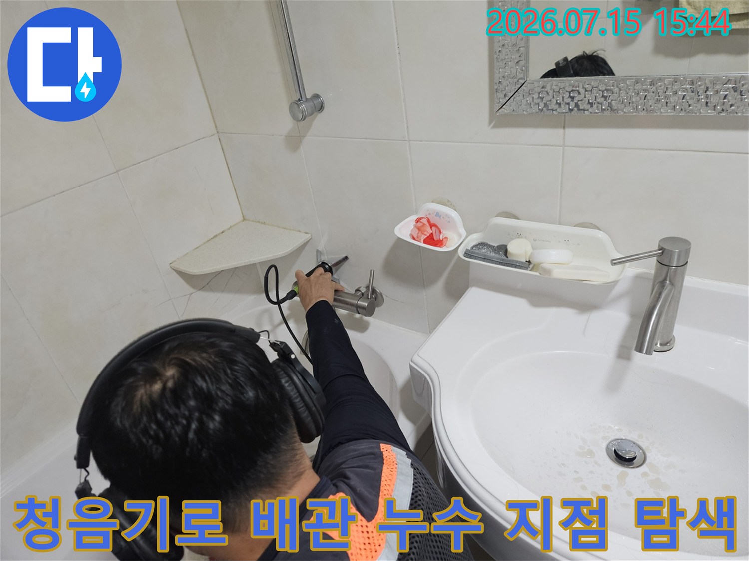 기술자가 청음 장비를 사용하여 세면대 하단 배관의 누수 위치를 정밀하게 탐지하는 모습