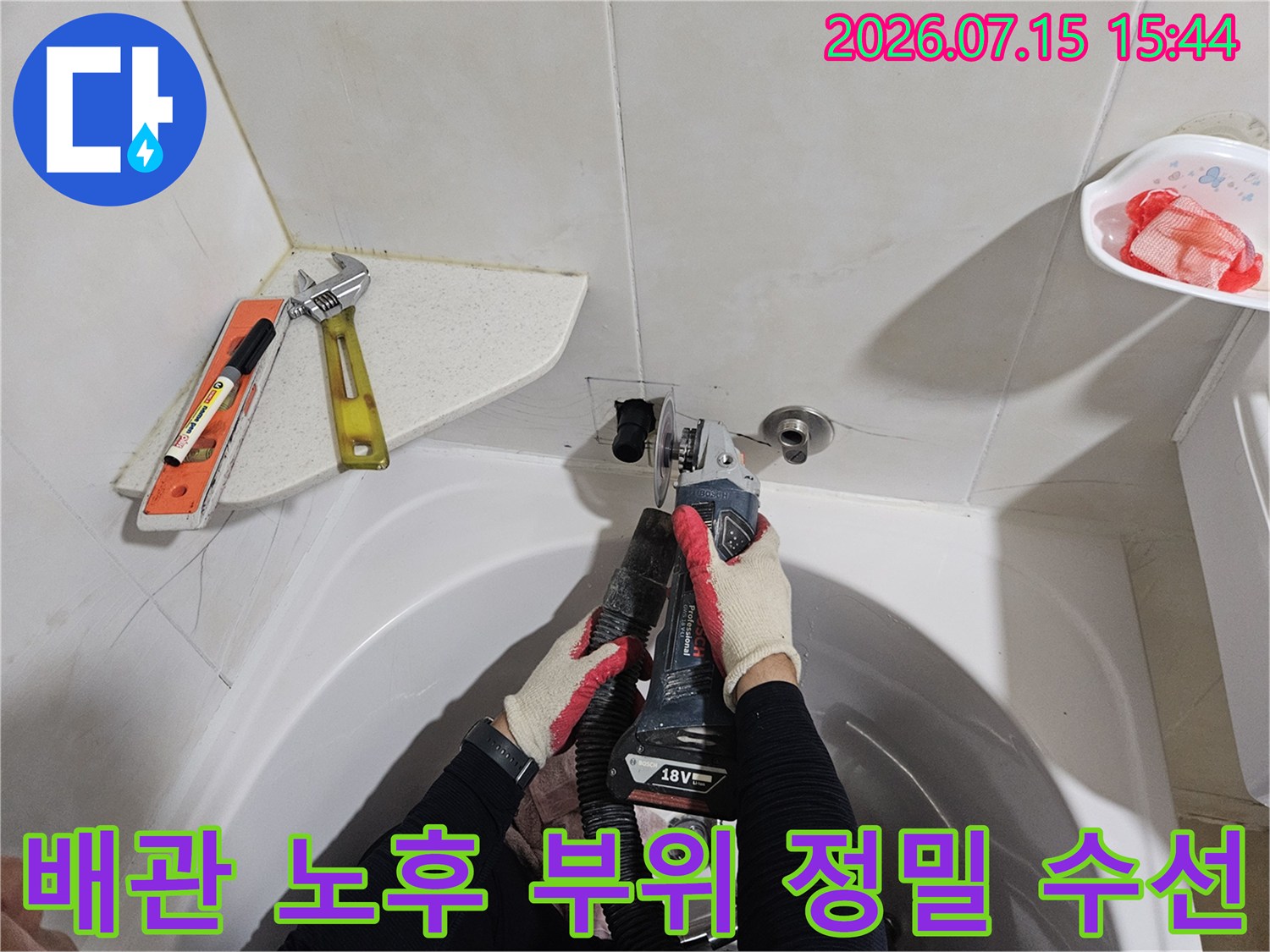 작업자가 세면대 아래에서 배관 연결부를 점검하고 전문적으로 수선하는 장면