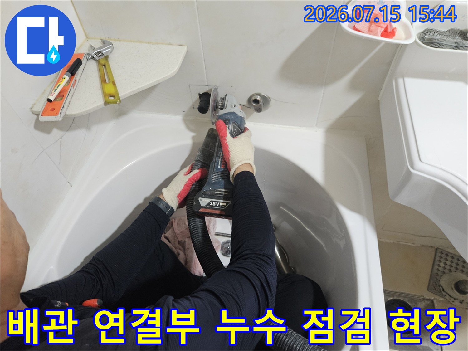 작업자가 세면대 하단 배관을 수리하기 위해 장비를 활용하는 모습