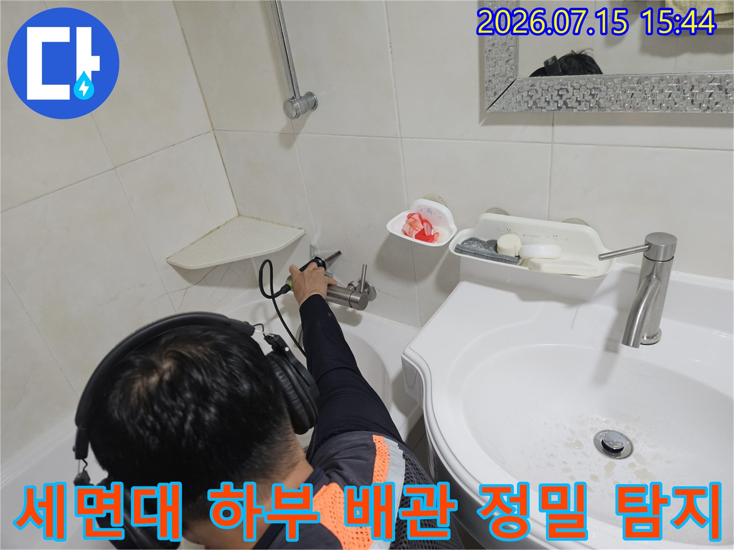 청음식 장비를 사용하여 세면대 밑 수도 배관의 누수 지점을 추적하는 모습