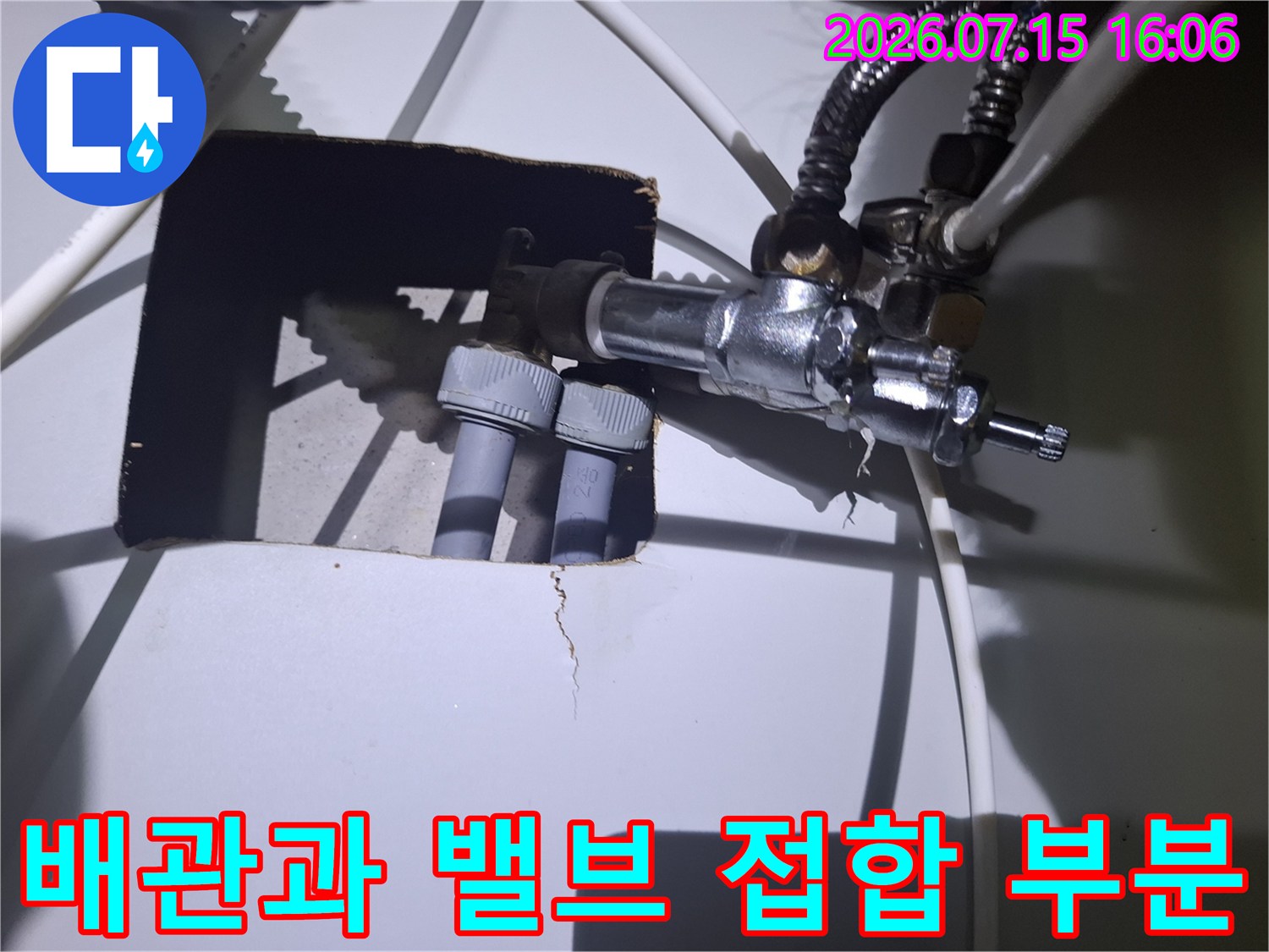 금속제 밸브와 두 갈래의 회색 배관이 연결된 보일러 하부 상세 사진