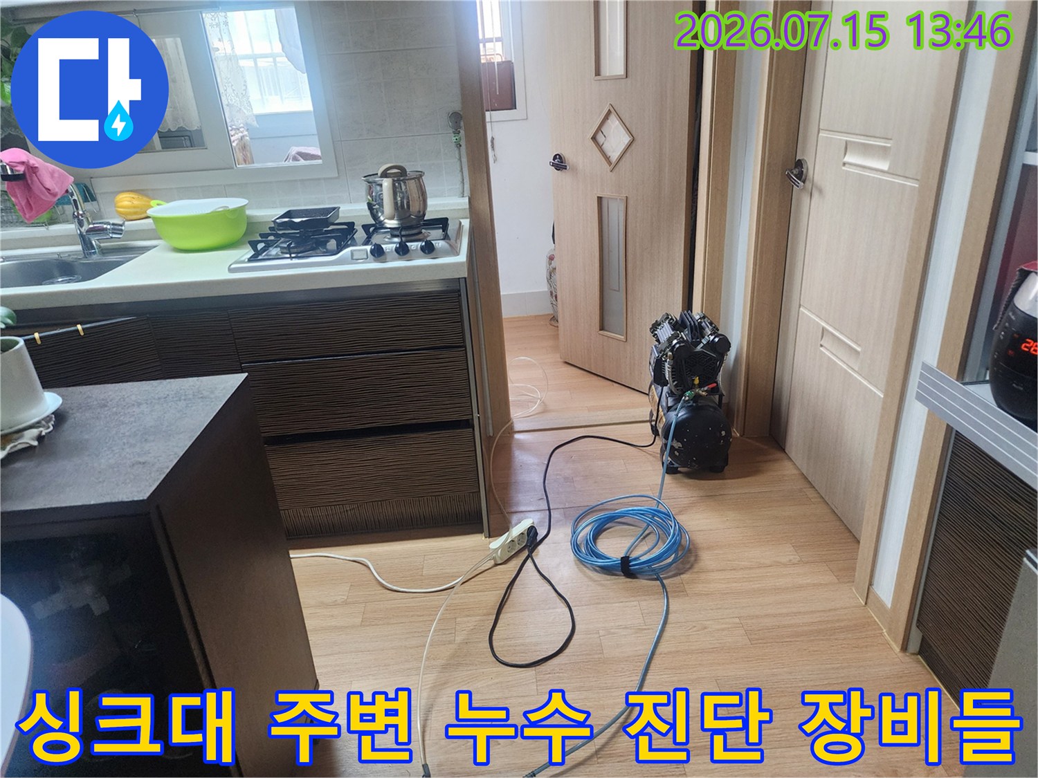 싱크대 하부장 옆 바닥에 펼쳐진 누수 탐지용 호스와 측정 장비 세트