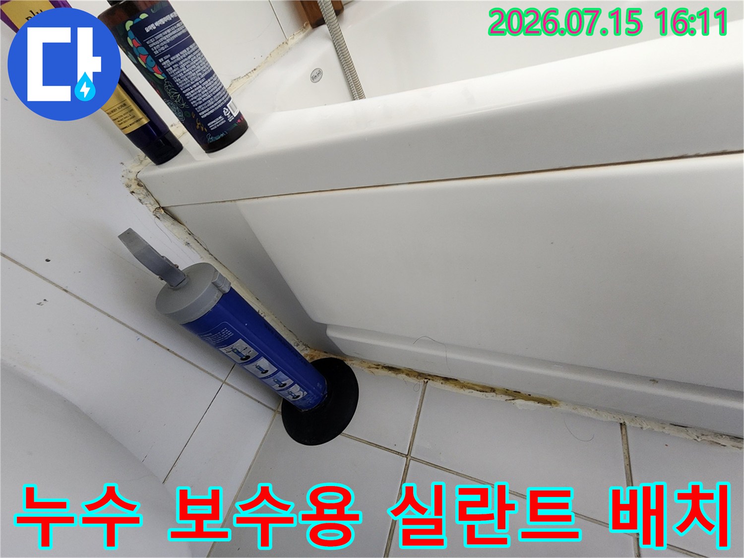 욕조 하단부의 갈라진 틈새 주변에 실리콘 건과 세척 도구가 놓인 장면