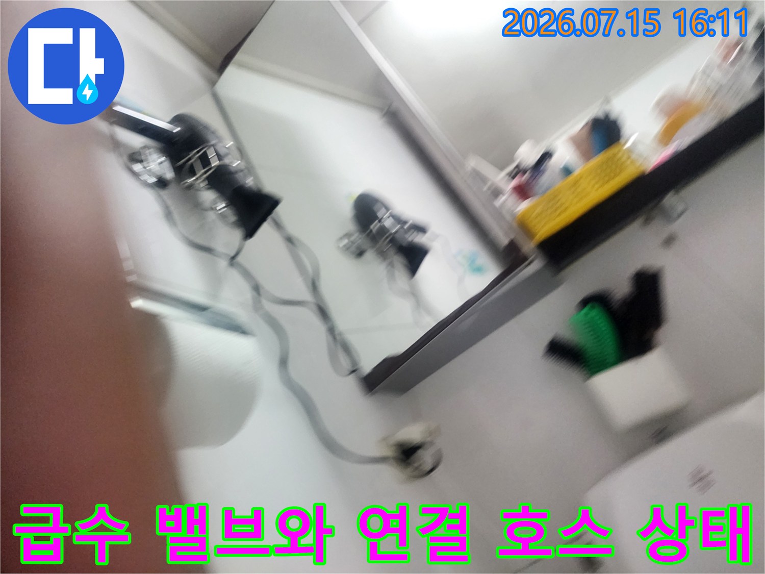 은색 수도 밸브와 유연한 급수 호스가 벽면에 연결된 장면