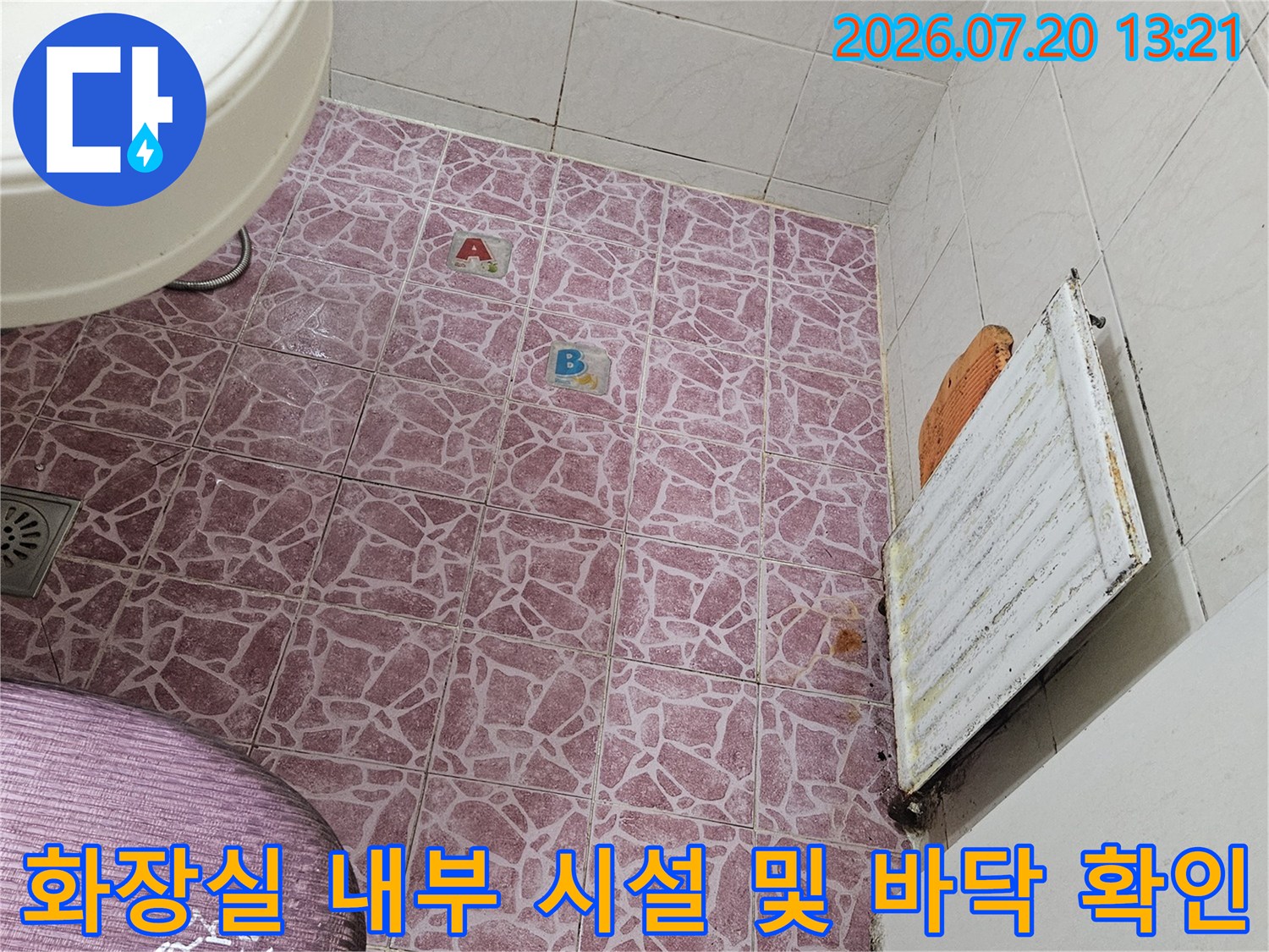 세척된 분홍색 타일 바닥과 상부의 배관 보호 조치가 된 설비 공간 촬영