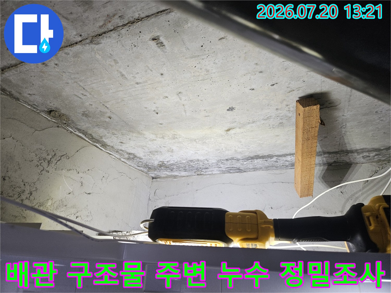 천장 내부의 노출 배관과 수직 목재 지지체 주변을 조사하는 장면