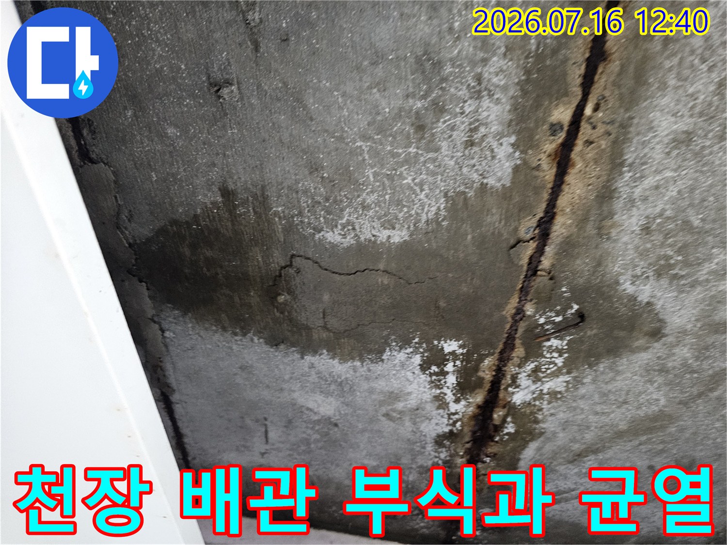 부식된 금속 배관과 콘크리트 천장의 누수 흔적 및 균열