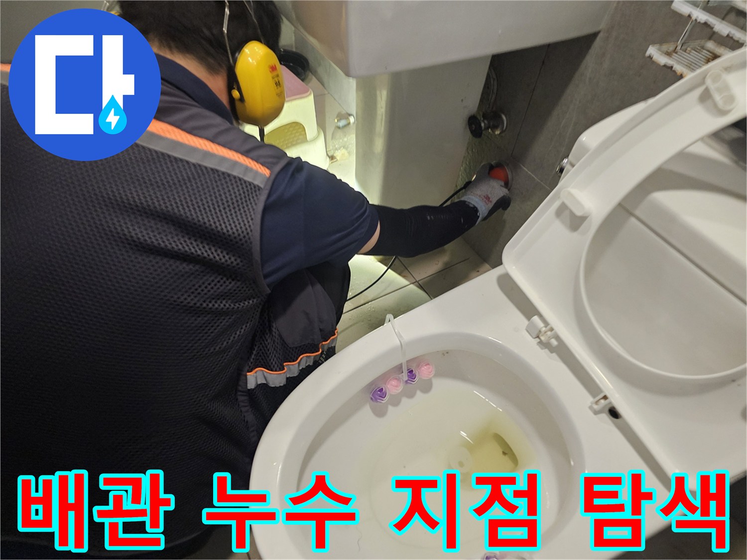세면대 아래쪽 급수 배관의 연결 상태를 면밀히 관찰하는 작업자