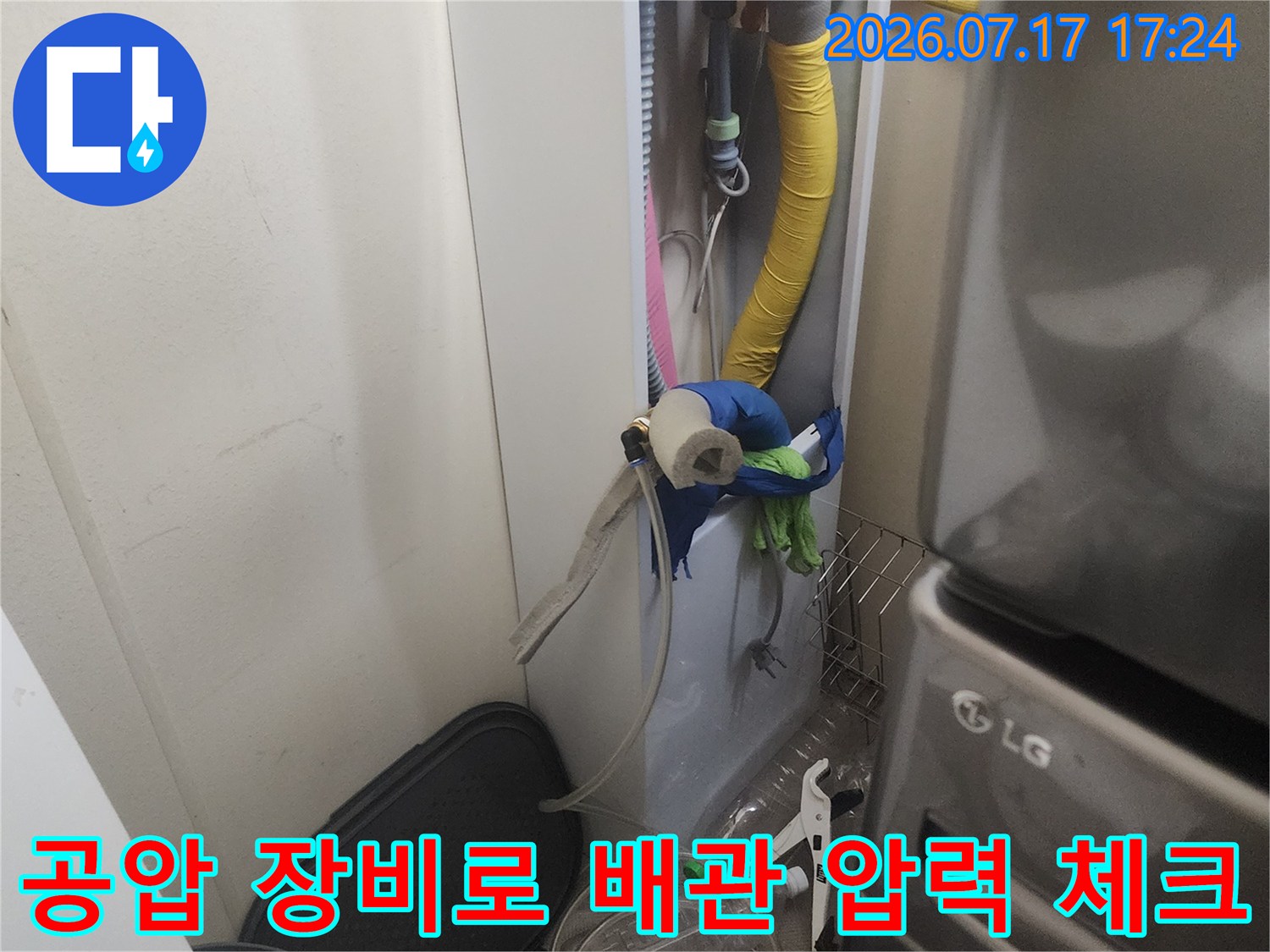 파란색 호스와 게이지를 활용하여 노출된 수도 배관의 이상 유무를 점검하는 장면