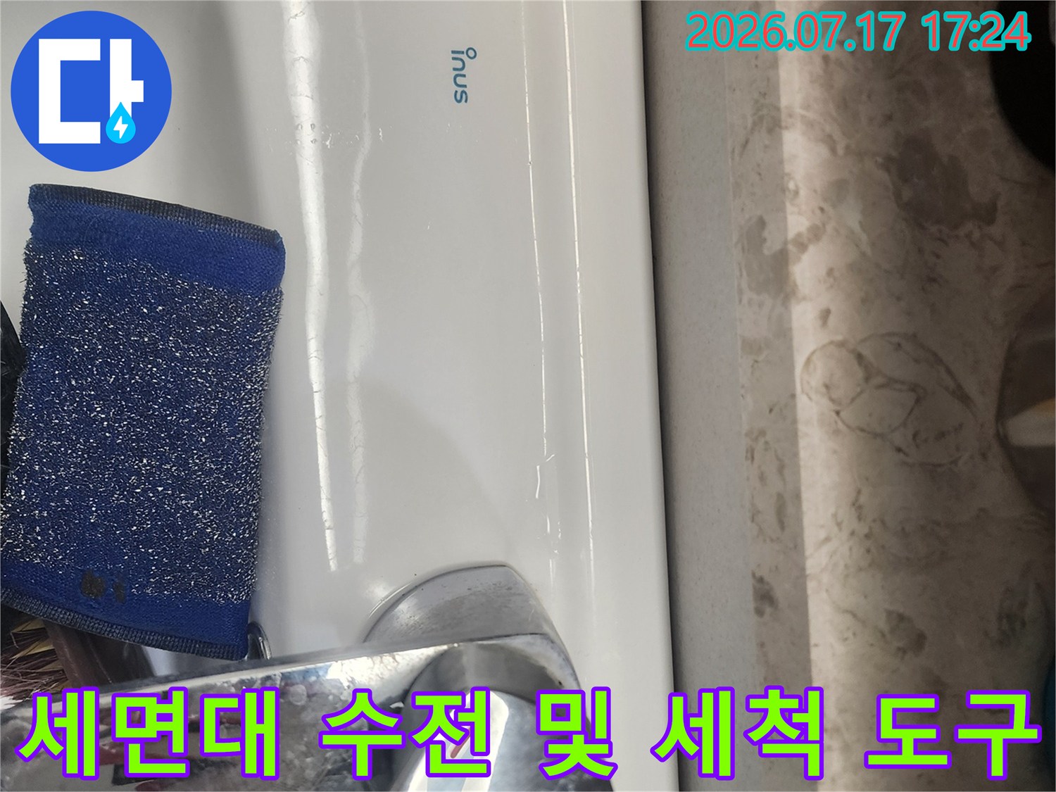 하얀색 세면대에 놓인 파란색 세척용 스펀지와 금속 재질의 수도꼭지