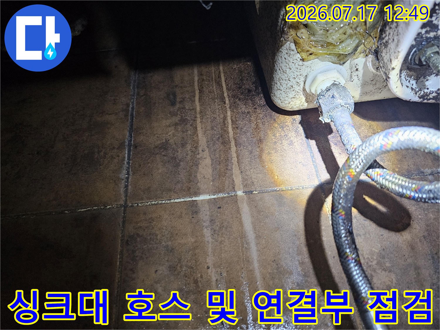 변색된 타일 배경의 싱크대 수전 배관과 금속 호스 상태