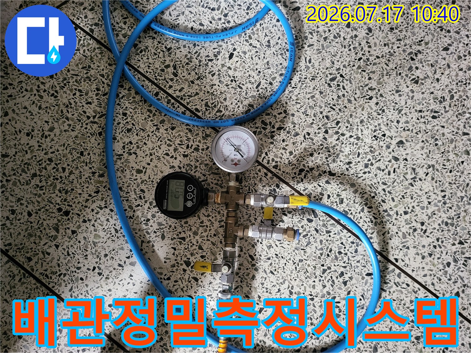 두 종류의 게이지와 파란색 호스가 연결된 배관 점검 시스템 장치