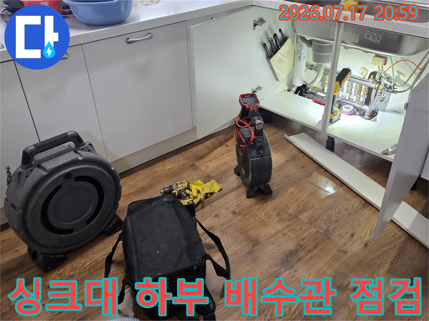 싱크대 밑 공간에서 가스 탐지기를 사용하여 배수관 누수를 정밀하게 확인하는 장면