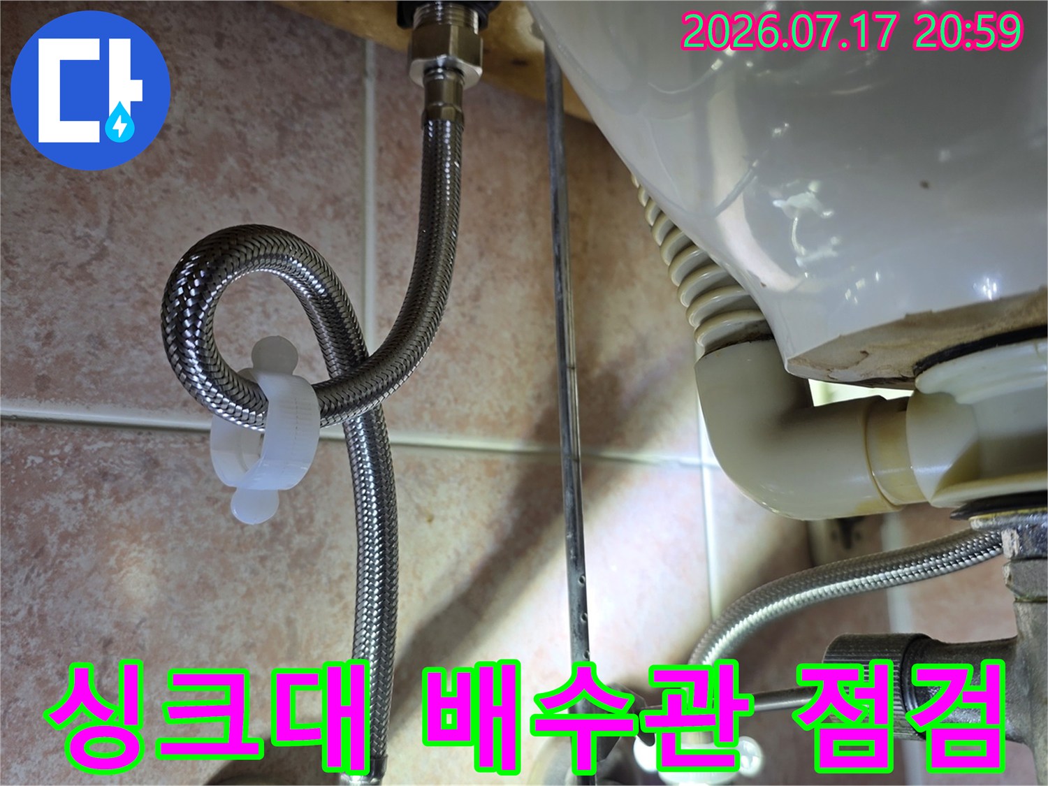 싱크대 하단부 노출된 주름 배수 호스와 연결 부위 점검 장면